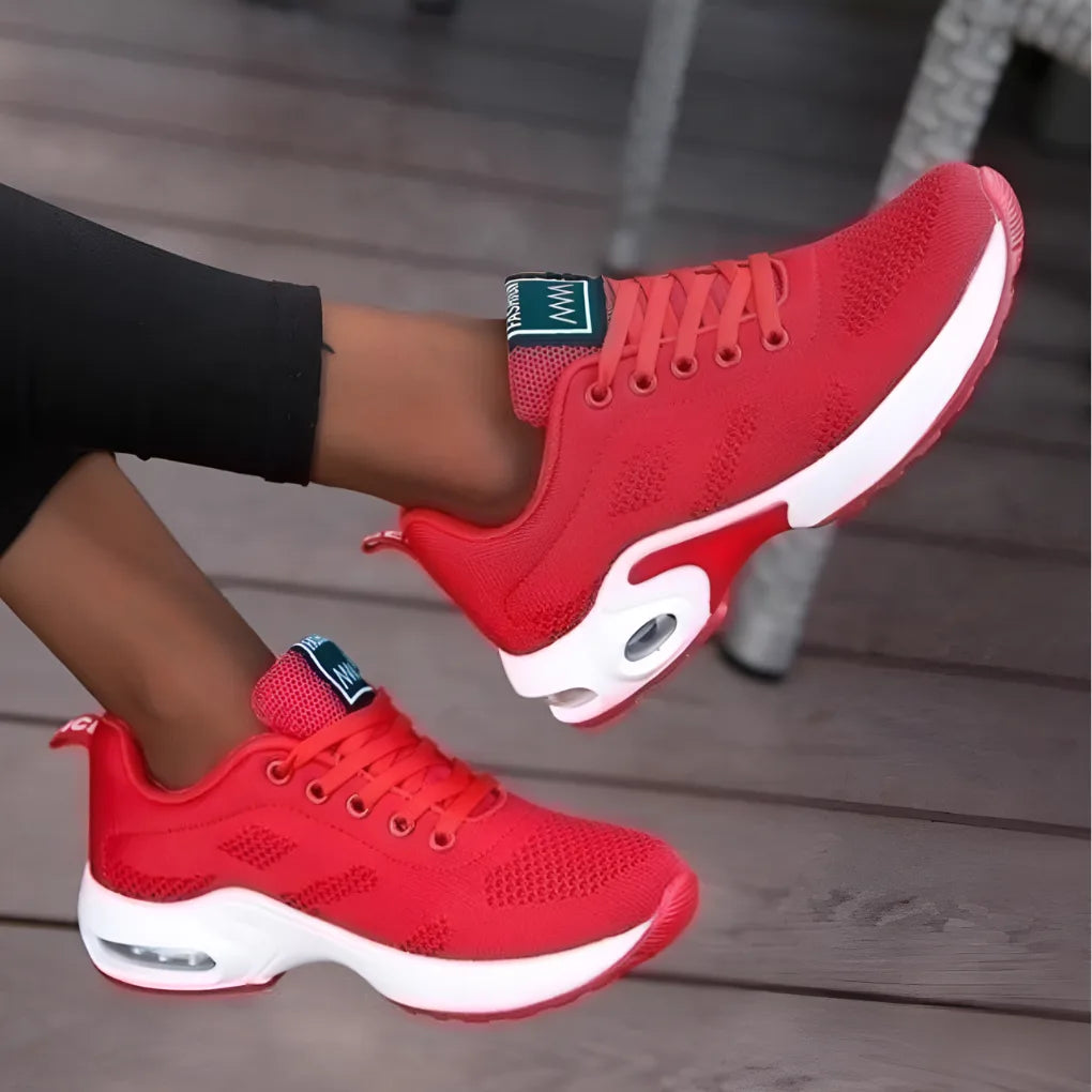 Side view of red mesh trainers with white sole and dark green heel tab, shown mid-step
