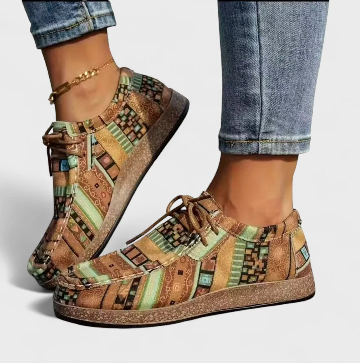 Front angle of khaki and green patchwork lace-up shoes with a cork-look wedge sole, worn with rolled denim.