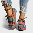 Close-up back view of colourful pink, blue and green patchwork lace-up shoes with a beaded anklet.