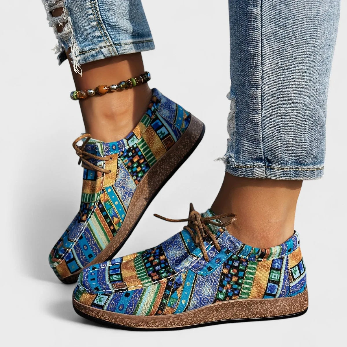 Side view of blue and gold patchwork lace-up shoes highlighting the textured sole and tan laces.