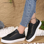 Black quilted lace-up trainers with white sole and metallic heel accent, styled with denim and a chain anklet.