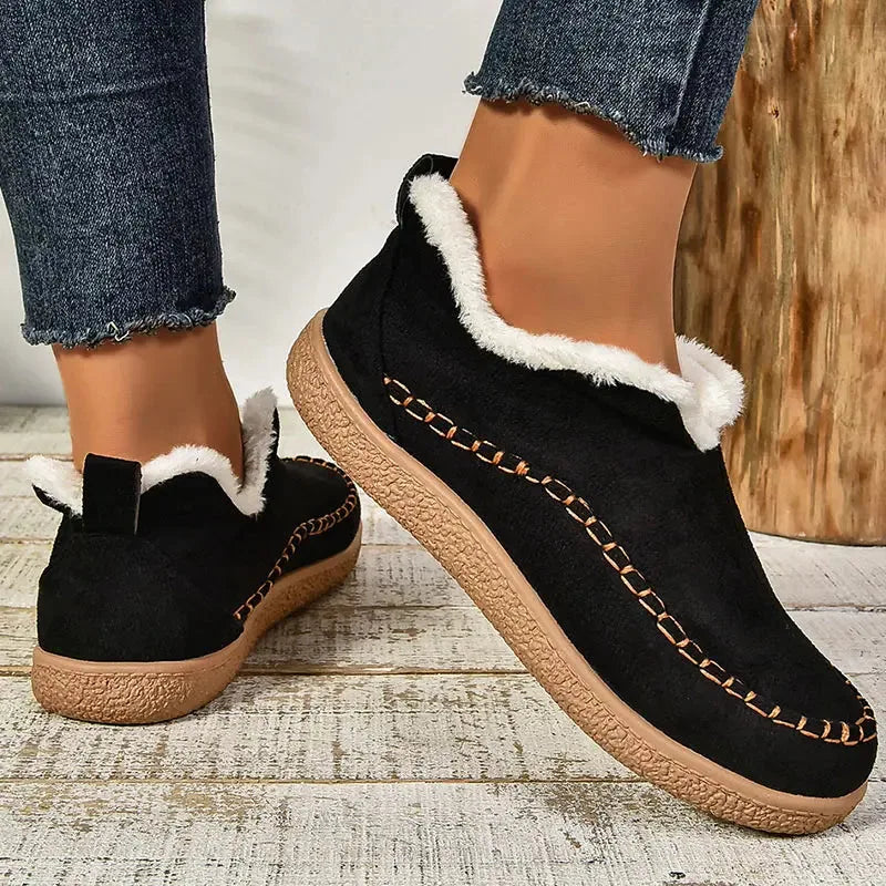 Black suede ankle boot with white fur lining and visible top-stitched seam detail on the upper