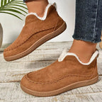 Pair of brown suede ankle boots on wooden floor showing rounded toe shape and textured outsole