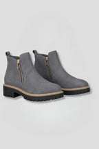 Front angled view of a pair of grey suede-effect ankle boots with gold-tone side zips and lug soles