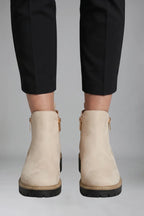 Close-up back view of beige suede-effect ankle boots showing the gold zip and tan-stitched sole trim