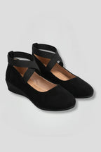Pair of black suede ballet flats with crisscross elastic straps and low wedge sole, front angle view