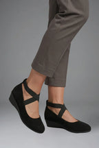 Side view of black suede ballet flat with crisscross elastic strap and low wedge heel