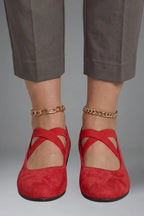 Front view of feet wearing red suede ballet flats with crisscross straps and gold anklet