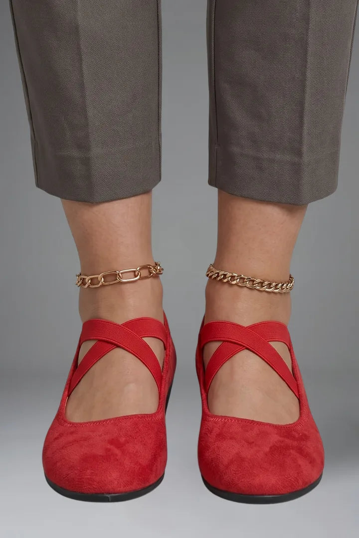 Front view of feet wearing red suede ballet flats with crisscross straps and gold anklet