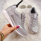 Overhead view of grey sparkling trainers laid flat on faux fur beside sunglasses and a watch