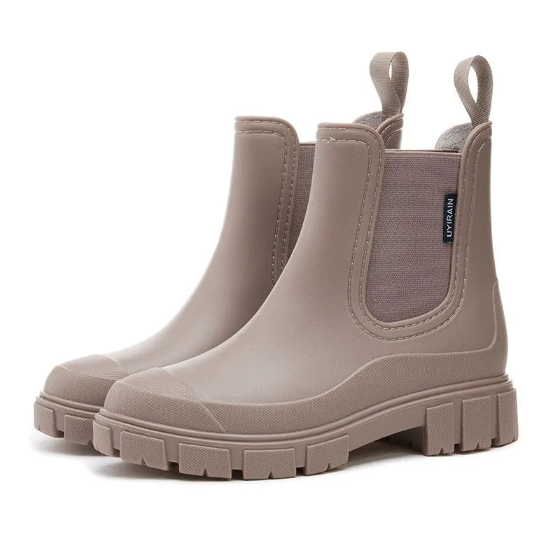 Beige Chelsea-style rain boots shown at an angle, highlighting the ribbed elastic gusset and stitched toe cap.