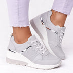 Grey wedge trainers with silver metallic panel and white sole, shown on foot with lilac jeans