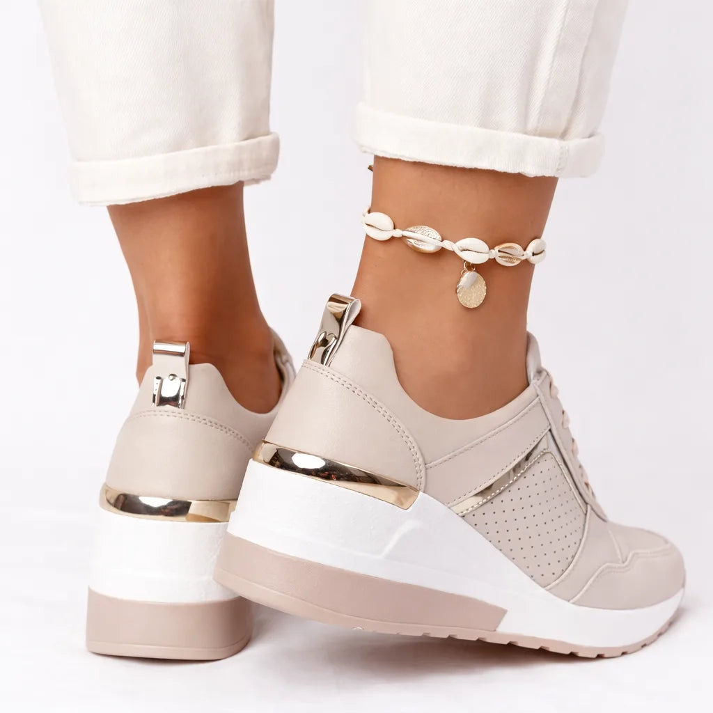 Back view of beige wedge trainers showing gold heel pull tab and white platform sole