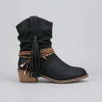 Studio side profile of a black slouch ankle boot with multicoloured braided wrap and tassel trim