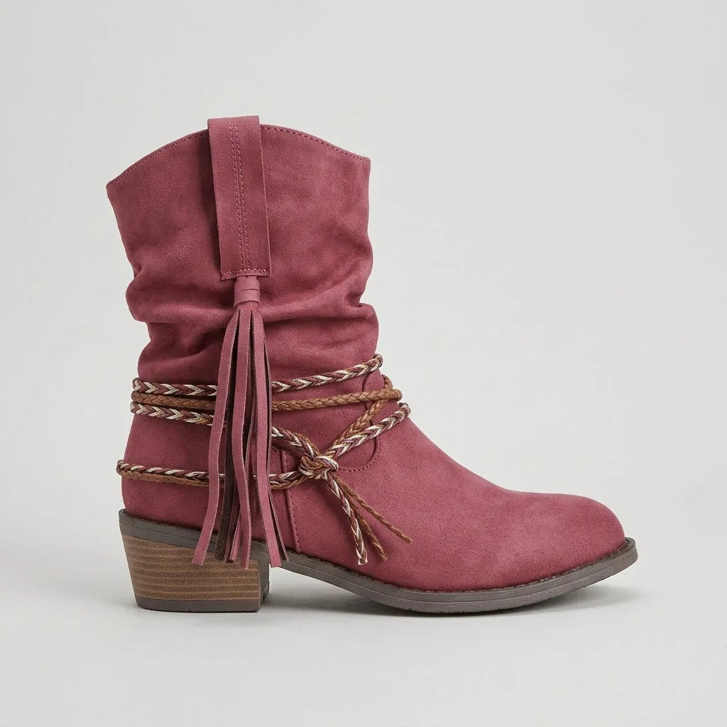 Studio side profile of a dusty pink suede-look slouch boot with braided ankle wrap and knotted tassel