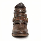Front view of brown studded ankle boot showing triple buckle straps and chain trim across the vamp