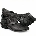 Pair of black distressed leather ankle boots with studded straps and chain accents, side by side