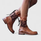 Side view of aged tan leather lace-up mid-calf boots worn on crossed legs with visible distressing
