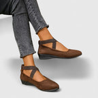 Brown suede ballet flats with crossed elastic ankle straps worn with cropped grey jeans, low wedge sole visible