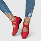 Red suede ballet flats with crisscross elastic straps worn with denim, paired with gold chain anklets