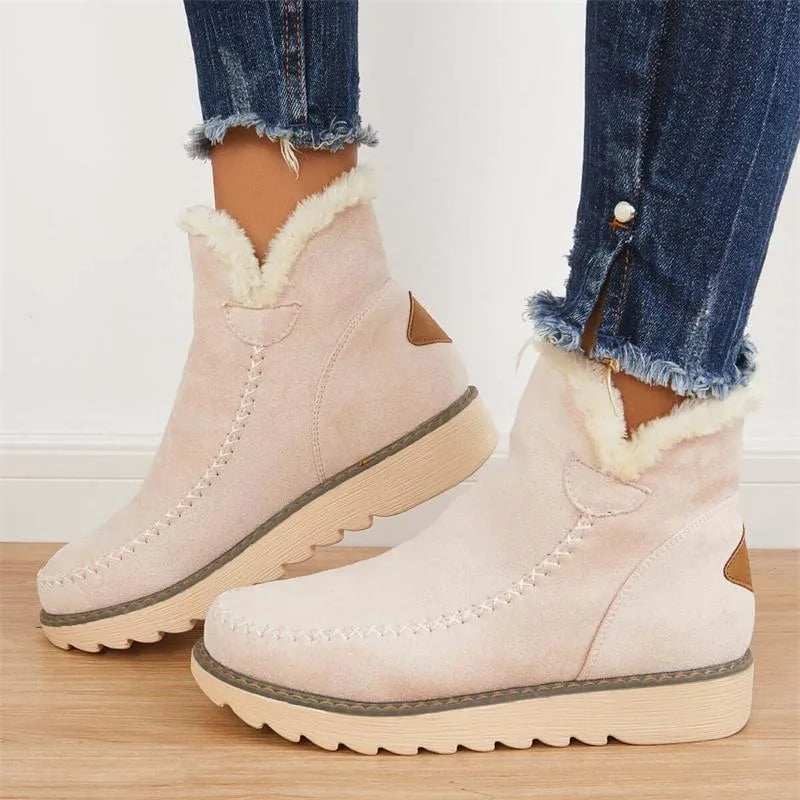 Side view of blush pink suede ankle boot with cream faux fur trim, whipstitch detail and tan heel patch, worn with jeans