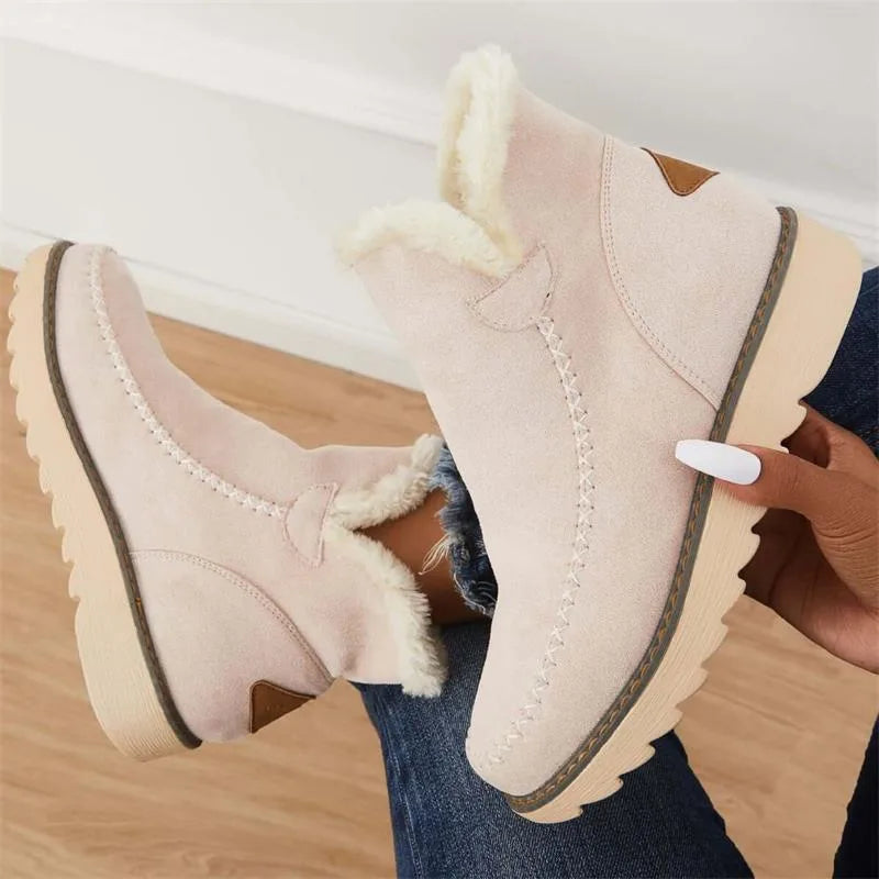Overhead view of blush pink ankle boots held by hand, showing plush faux fur lining and ridged platform sole
