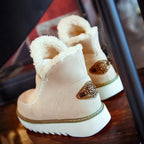 Back angled view of cream ankle boot with faux fur collar and metal emblem on the heel counter