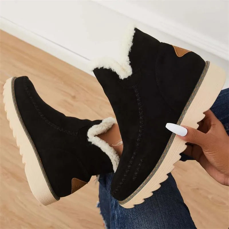 Close-up of black ankle boots held together, highlighting the faux fur lining and chunky ridged sole