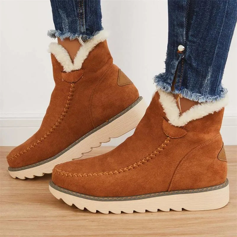 Side view of tan brown suede ankle boot with cream faux fur trim worn with cuffed denim jeans