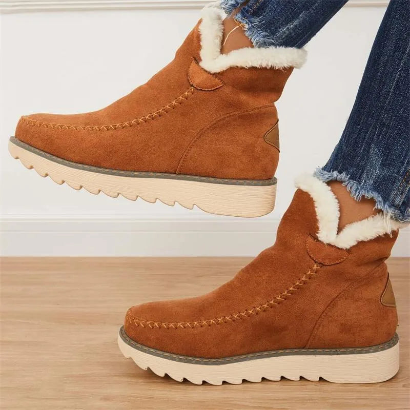 Model standing and lifting one foot to show the tan brown ankle boot's sole tread and stitched side seam