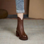 Close-up side view of a brown leather Chelsea boot worn with rolled-up jeans, showing block heel and platform sole
