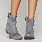 Grey suede cowboy ankle boots shown from the front with stacked heel and weathered leather sole.