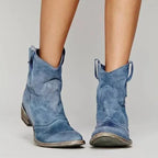 Blue suede cowboy ankle boots showing distressed finish, curved heel and seam detailing at the front.