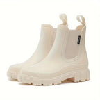 Cream Chelsea rain boot pair viewed from the side, highlighting chunky ridged sole and stitched toe cap
