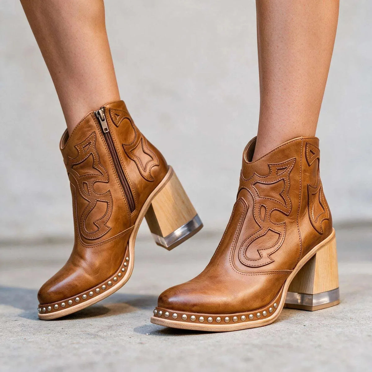 Studio shot of tan leather ankle boots highlighting the studded platform edge and clear-topped wooden heel