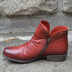 Deep red leather ankle boot with ruched upper and matching zip pull, shown in profile.