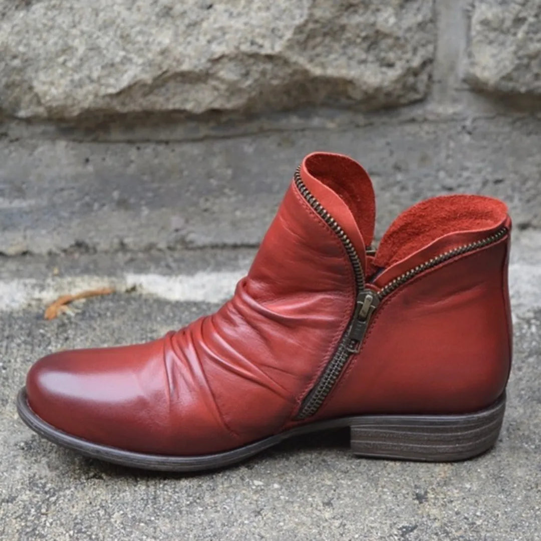Deep red leather ankle boot with ruched upper and matching zip pull, shown in profile.