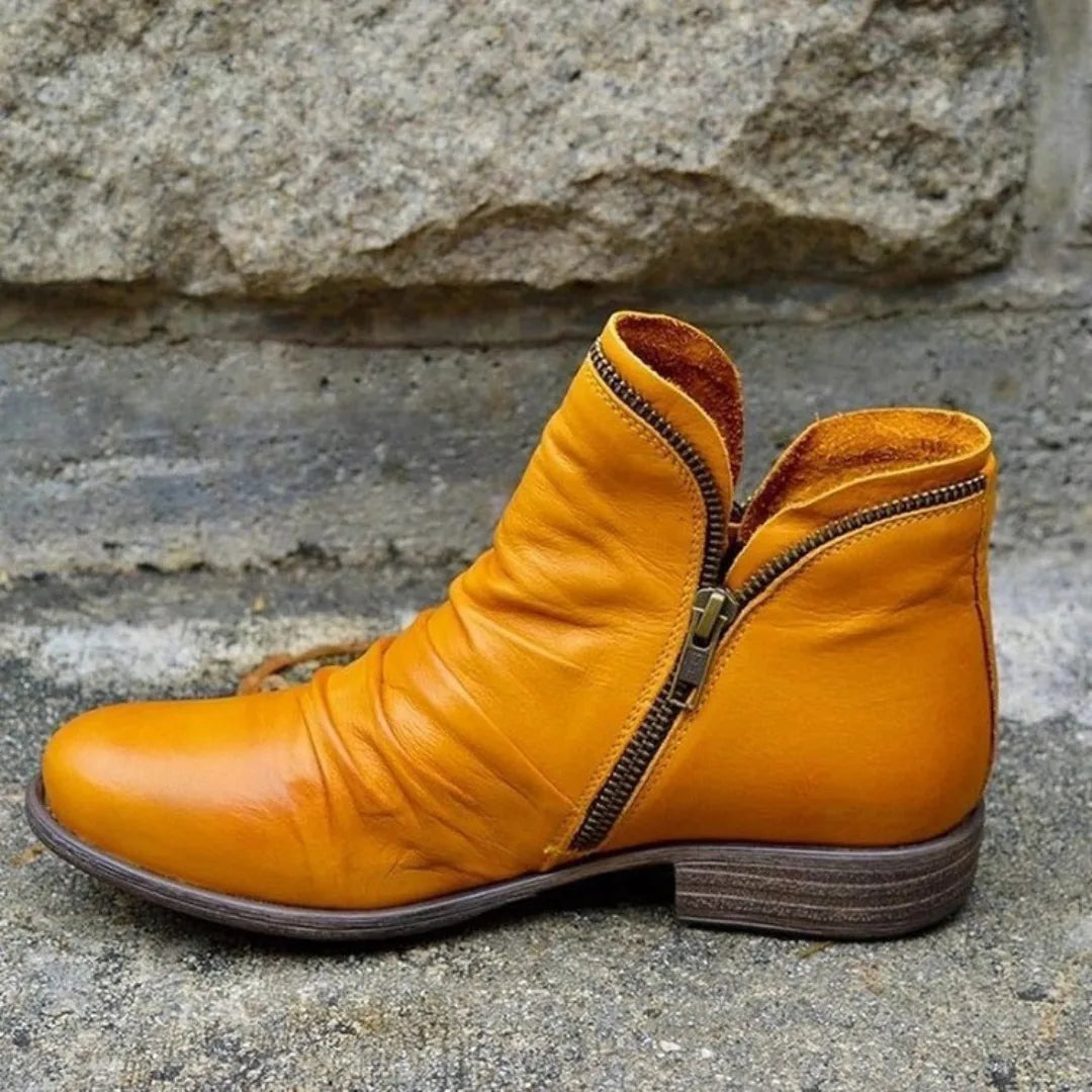 Mustard yellow leather ankle boot with slouchy folds and open zip revealing the suede lining.