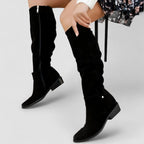 Black suede knee-high slouch boots worn together showing side zip and low block heel