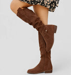 Close-up side view of black suede knee-high boot highlighting zipper and slouched shaft