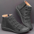 Black leather ankle boots with cross-laced front and matching black zip, shown on a dark backdrop