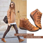 Model wearing tan brown lace-up leather ankle boots styled with dark trousers and an oversized jumper