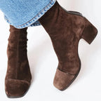 Close-up of brown suede ankle boots with a slouchy ruched shaft and square toe, worn with straight-leg jeans