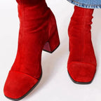 Red suede ankle boots with contrast toe cap and block heel, viewed from above while worn with denim