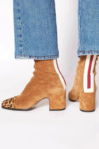 Tan suede ankle boots with cream and red zip trim at the back, paired with straight jeans