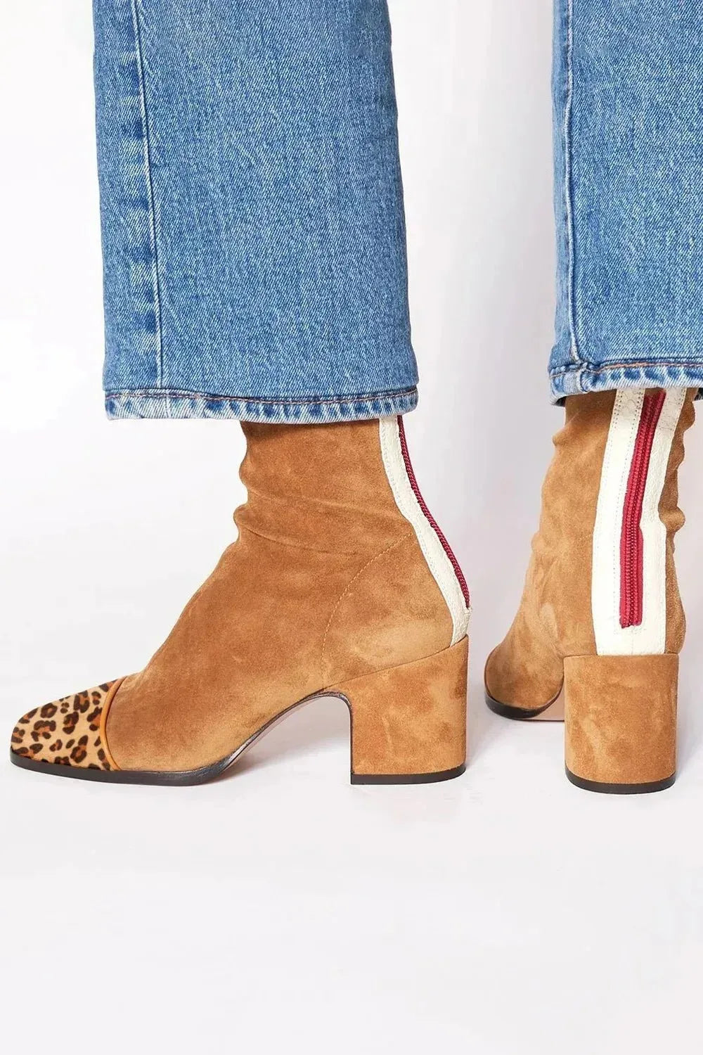 Tan suede ankle boots with cream and red zip trim at the back, paired with straight jeans