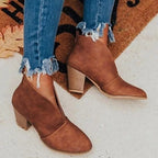 Close-up of brown faux-suede V-cut ankle boots with stacked block heel, worn with frayed denim jeans